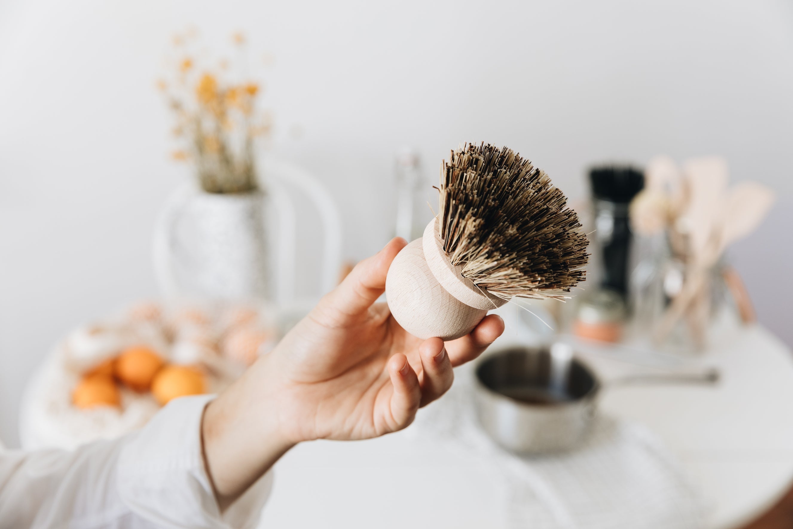 Hand holding up a wooden dish brush with natural bristles.