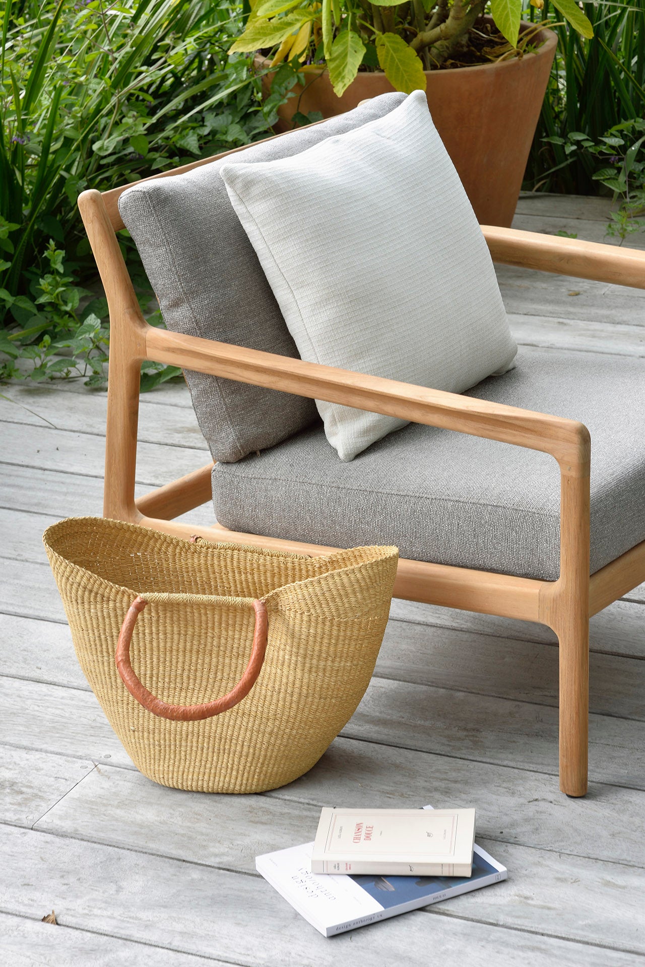 Close-up of the back and arm of a wooden-framed chair with gray fabric cushion