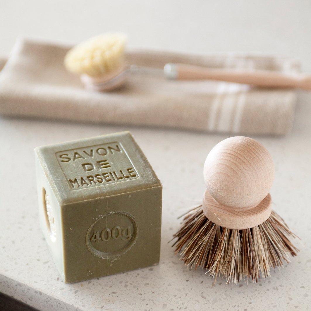 Savon de Marseille cube soap next to natural dish wooden brushes.
